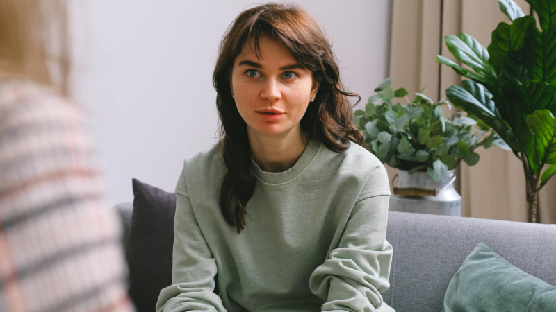 Woman sitting on couch talking to a counsellor